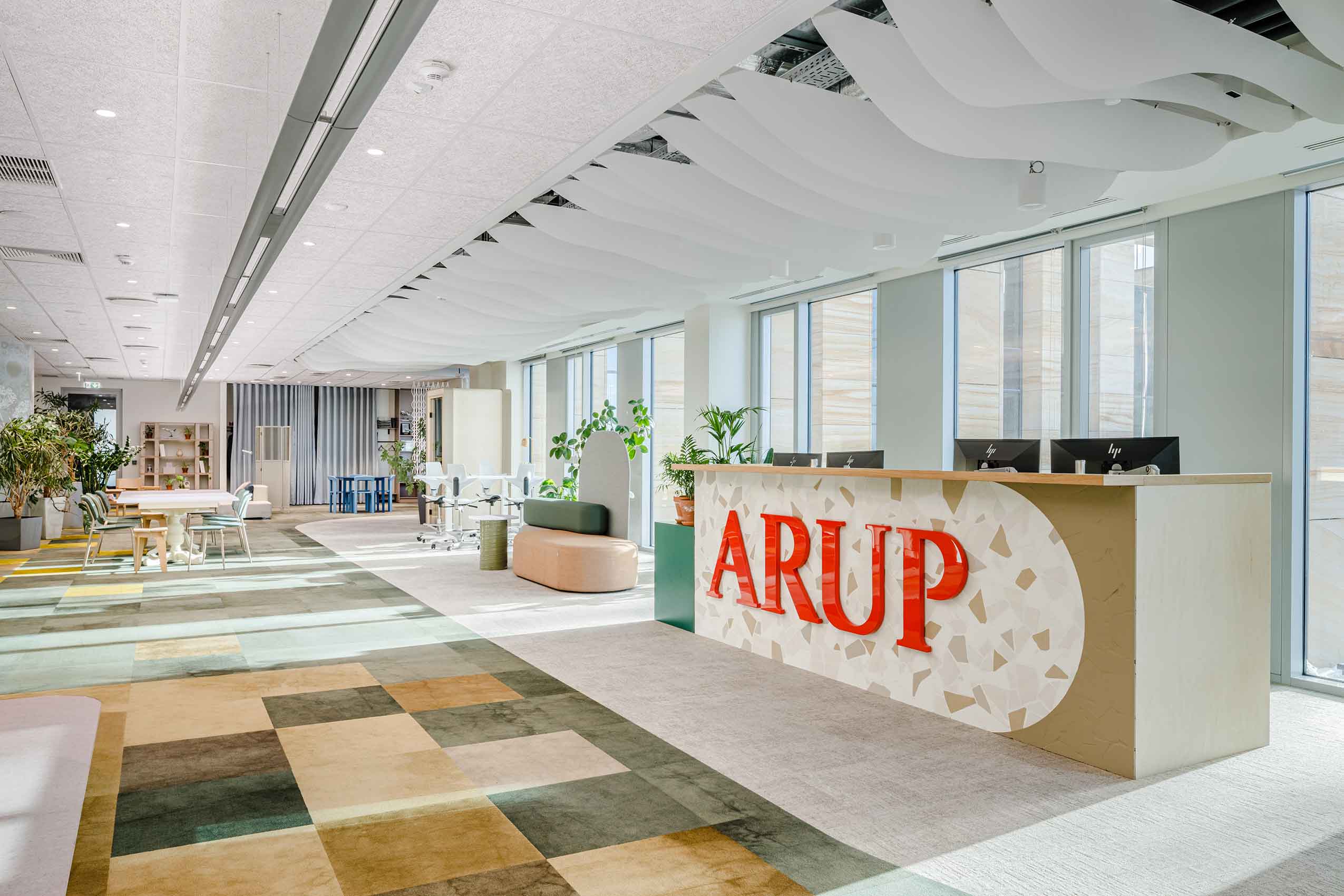 The Foyer in Arup's new office, with their bran dname on the reception desk and open space including seating.