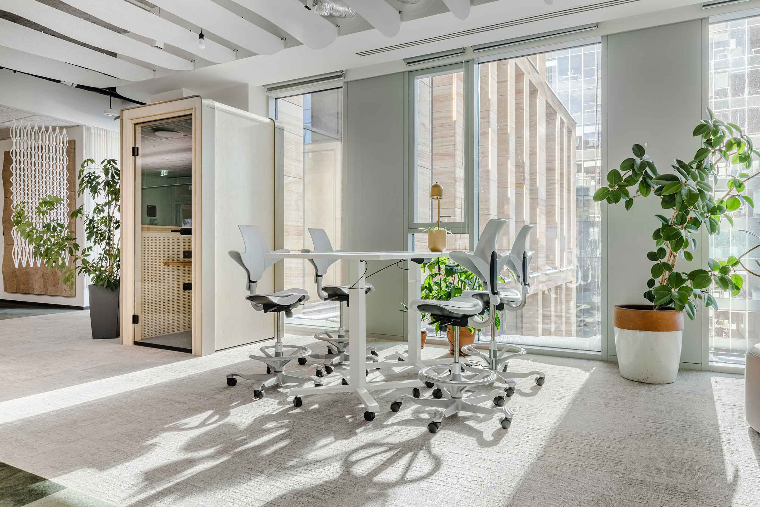 4 HÅG Capisco Puls chairs around a table in arups new office space. light is shining through the window on the bright and airy space.