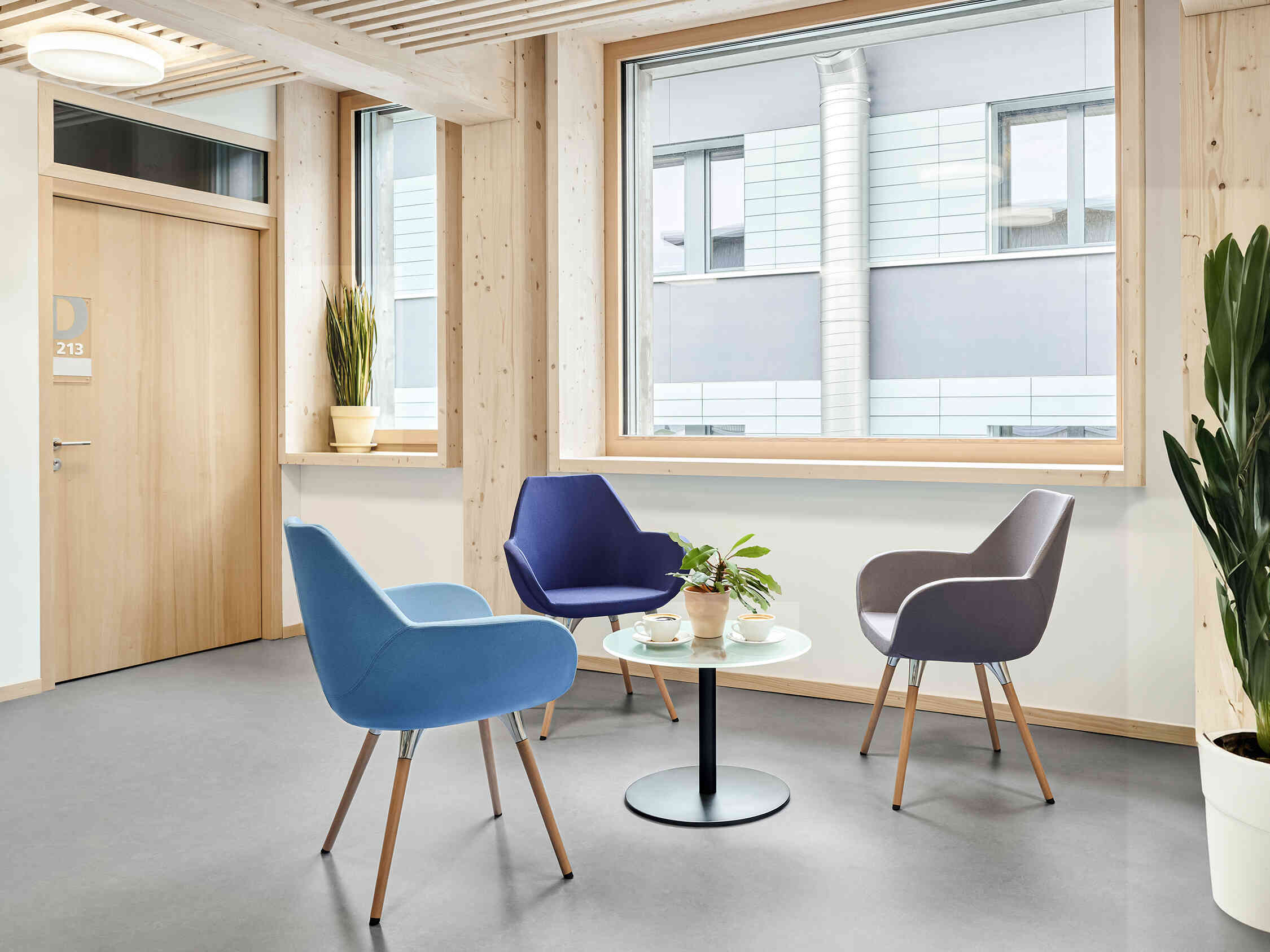 3 blue Profim fan chairs around a small table with a plant on it, in a social space at Davos WSL