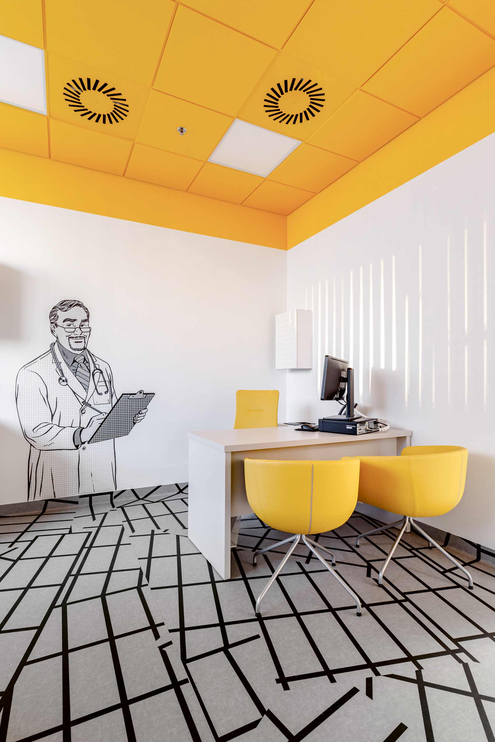 white and yellow hospital consultation room with yellow profim chairs and a cartoon drawing of a doctor on the wall