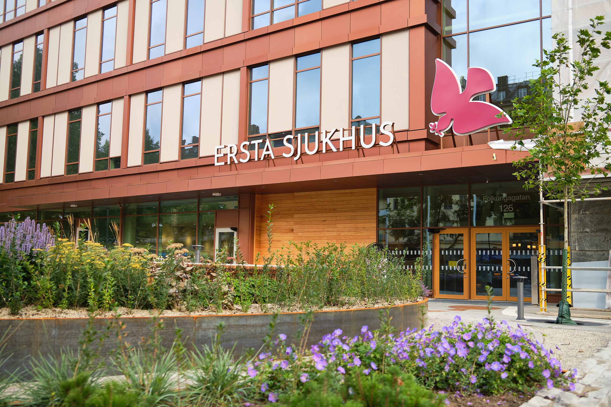 Exterior photo of entrance of ersta hospital - the walls are a welcoming beige colour with big tall windows