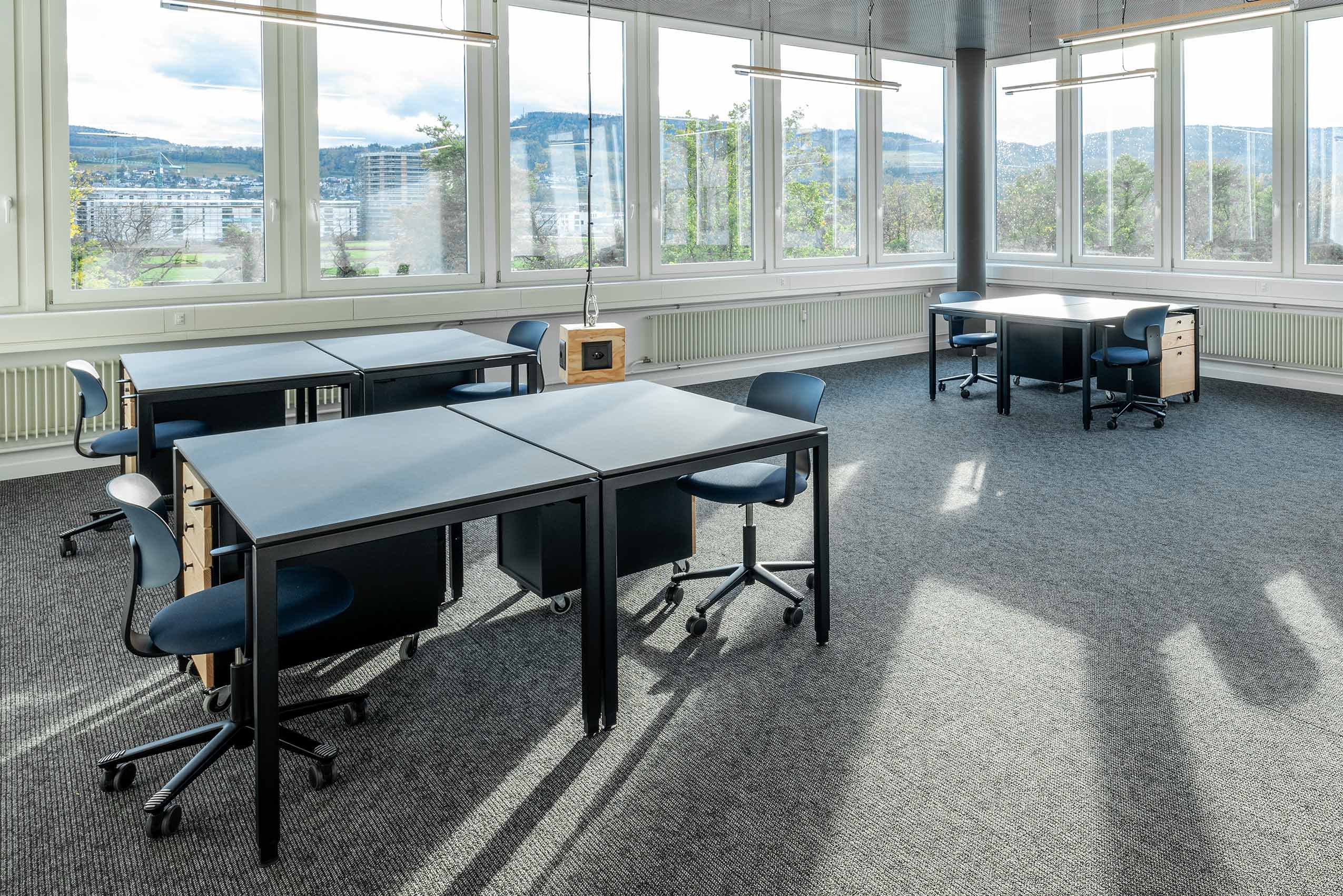 a corner of windows, in a room with 3 tables and HÅG Tion chairs around the tables