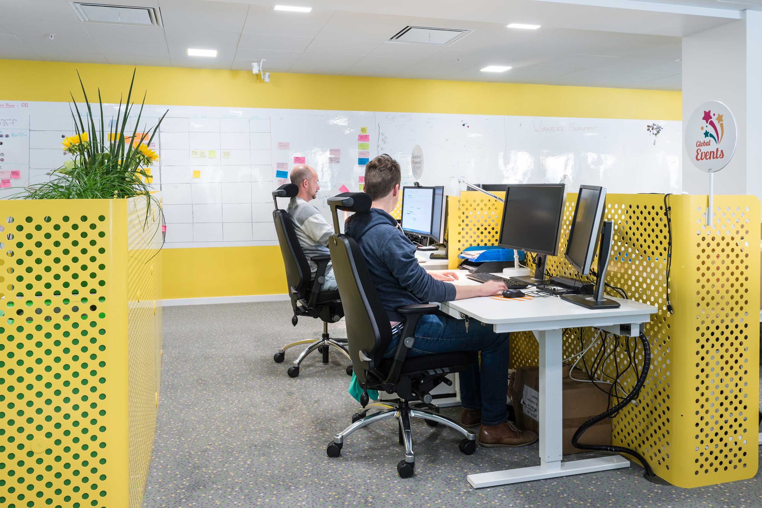 2 people sat in RH Logic chairs in King's office, with yellow walls and furniture