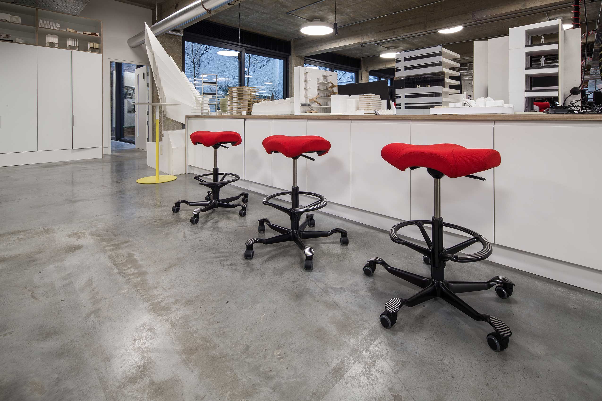 Angle 3 of interior of make architects office, with bright red HÅG Capisco chairs