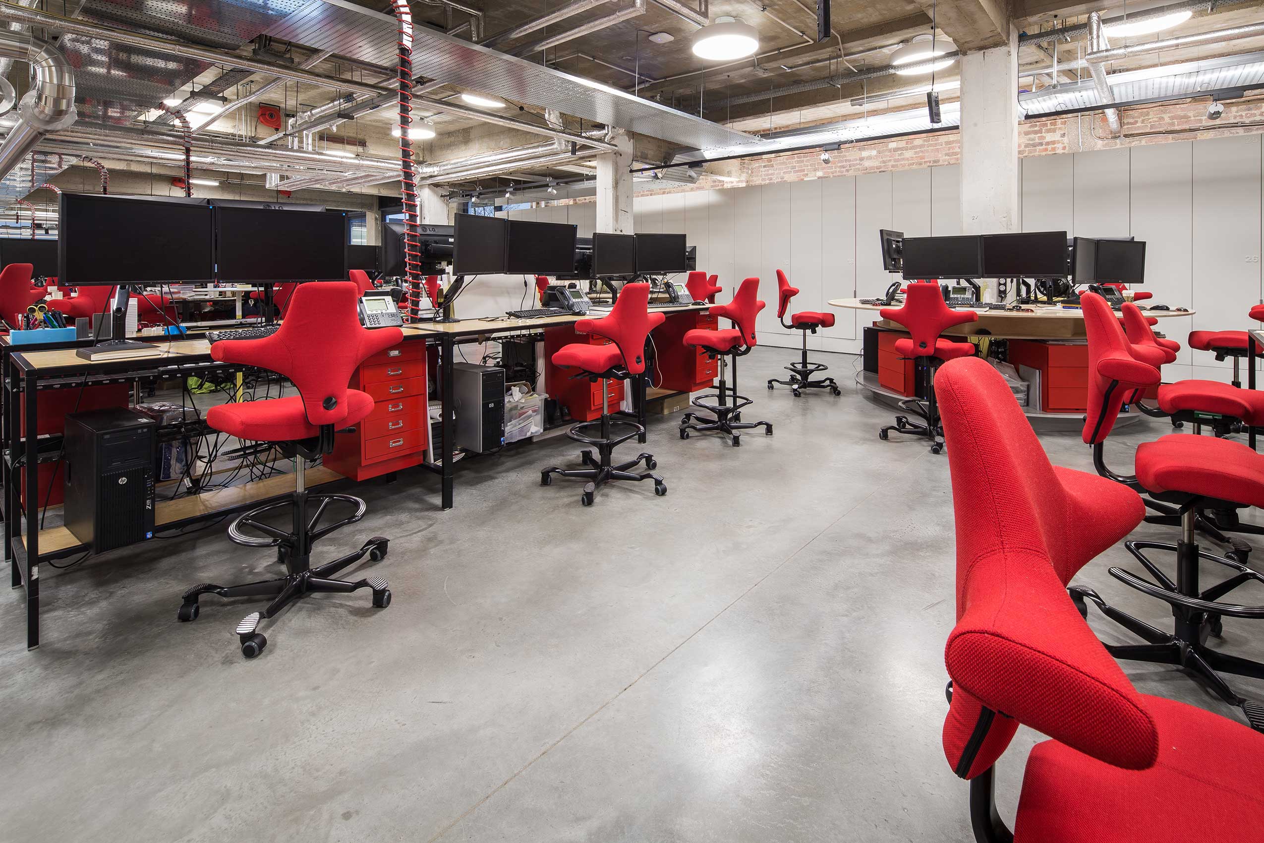 Angle 6 of interior of make architects office, with bright red HÅG Capisco chairs