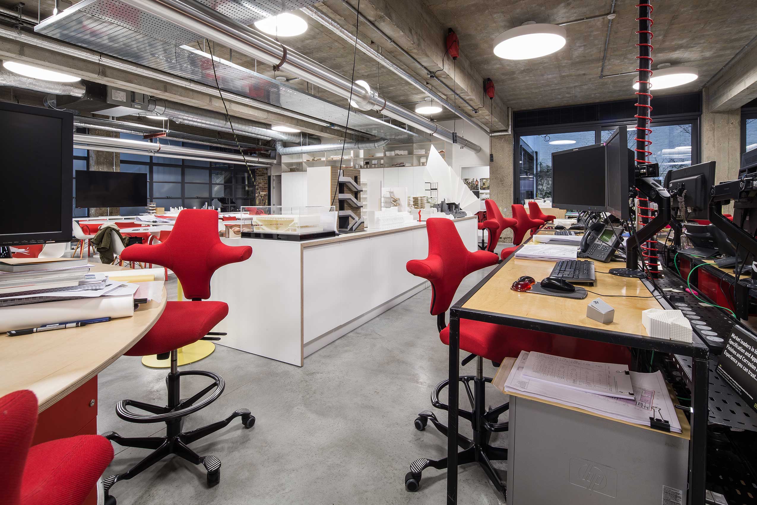 Angle 7 of interior of make architects office, with bright red HÅG Capisco chairs
