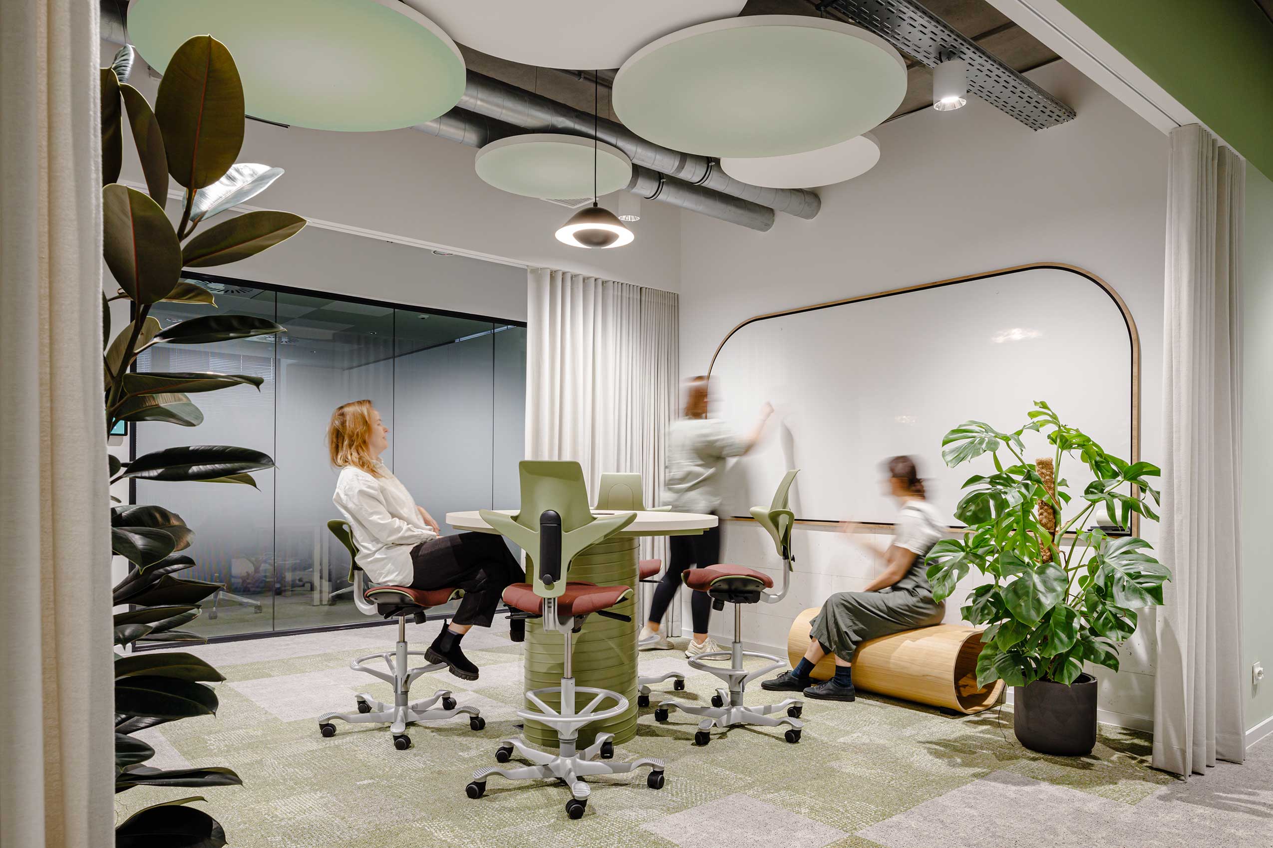 several people in an office collaboration space with HÅG Capisco Puls chairs around a table