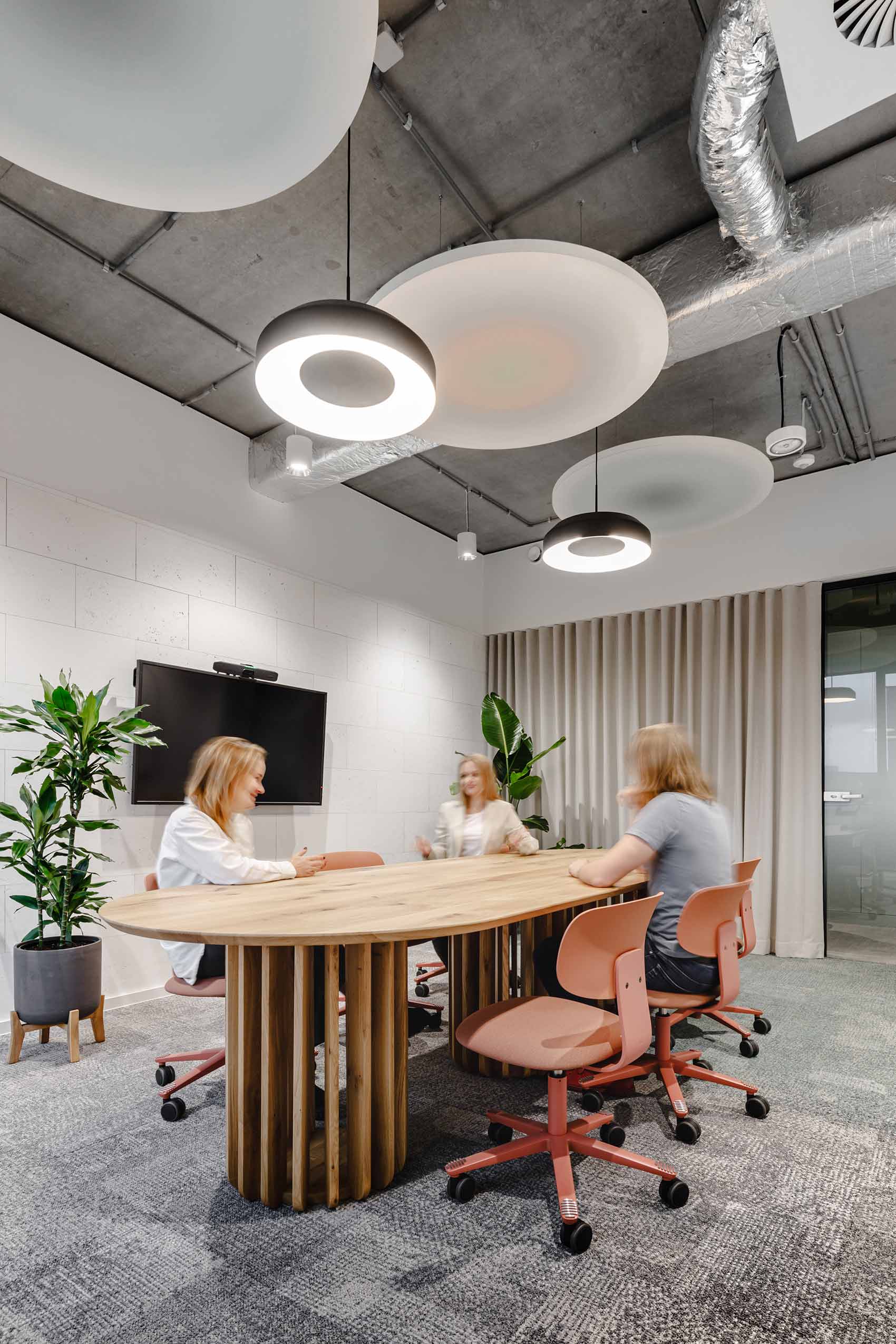 3 people sat in HÅG TIon chairs around a wooden table in an office
