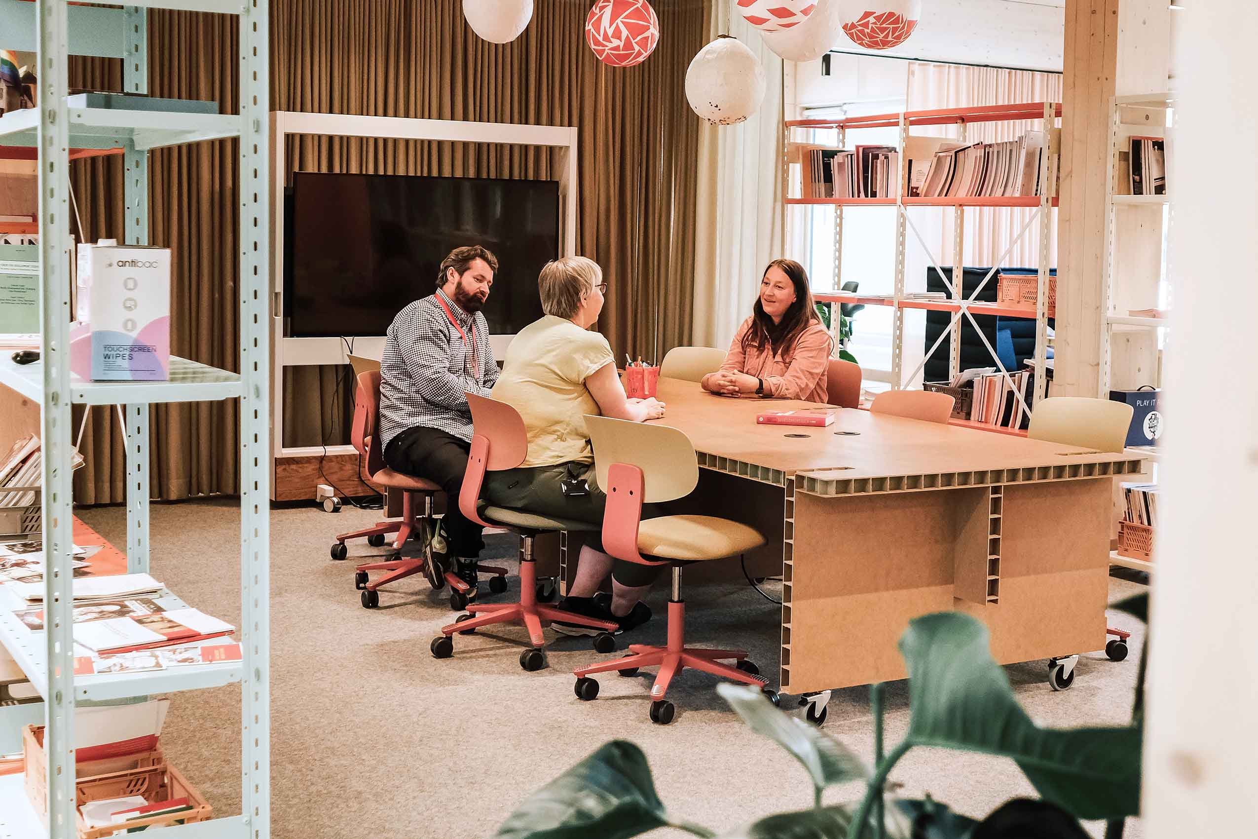 A group of people sat around a table in colourful HÅG Tion chairs