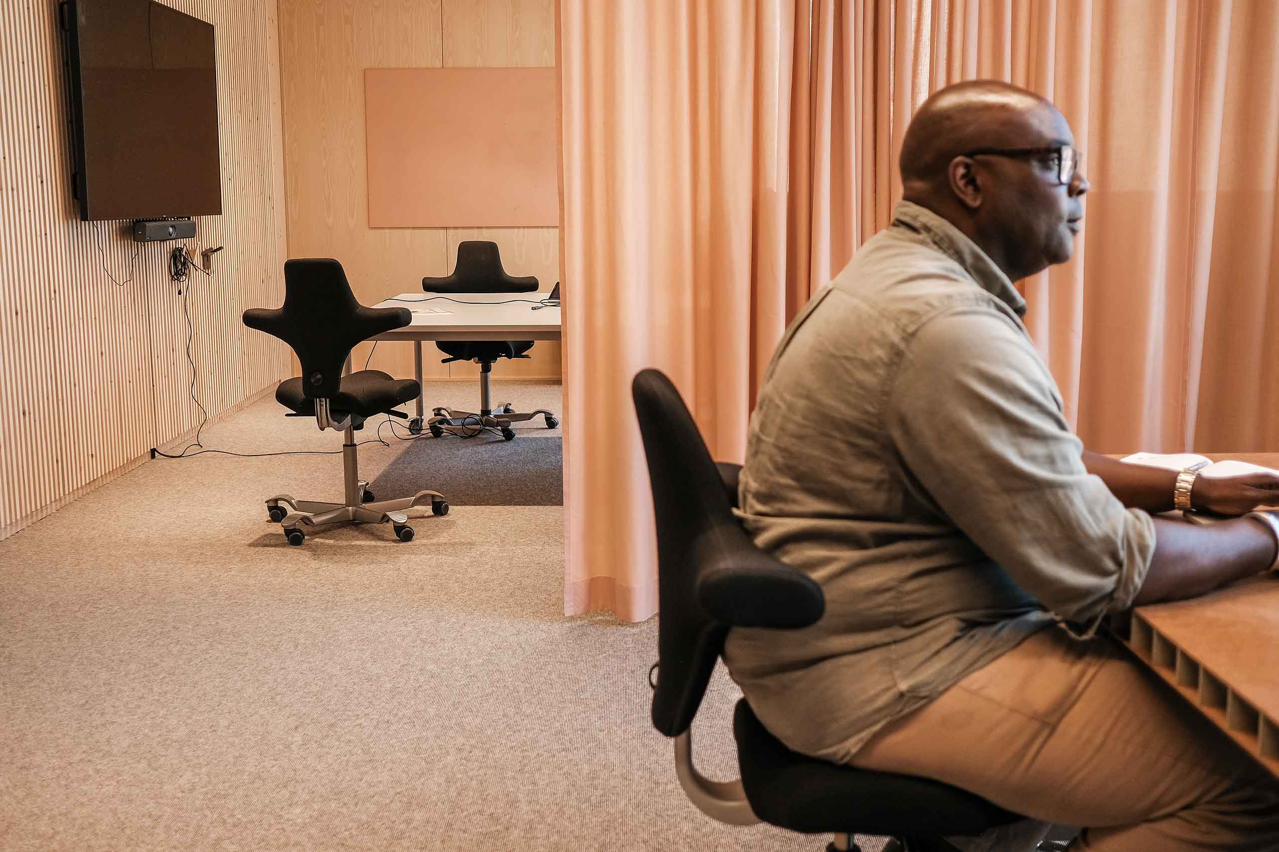 A man sat at a desk in a black HÅG Capisco chair in the Redd Barna office in Oslo