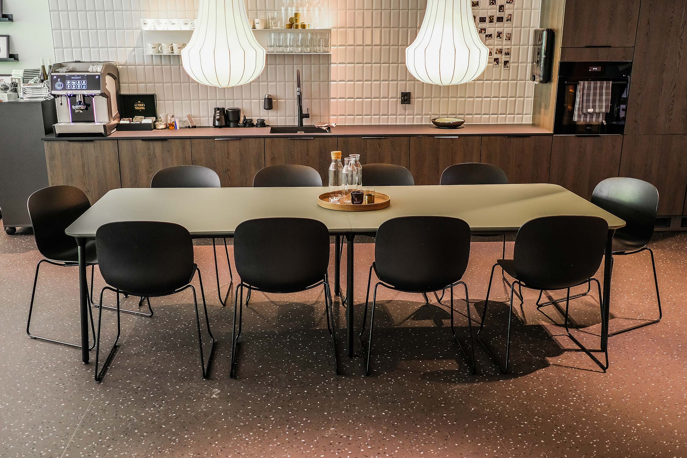 10 black Profim Noor chairs around a table in a kitchen area at Soco & Gnist's Oslo office