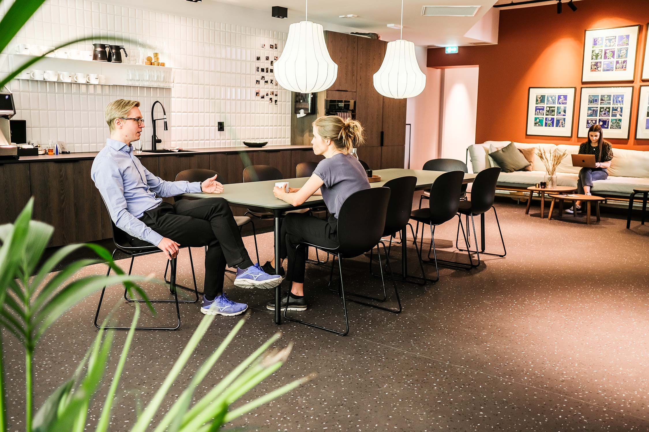 Angle 2 of 2 people sat at a table on RBM Noor chairs, in an office collaboration area 