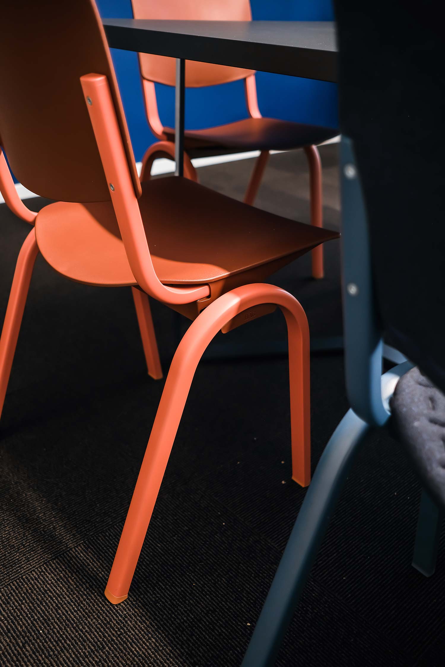 Close up of one red and one blue HÅG Celi chairs at a table