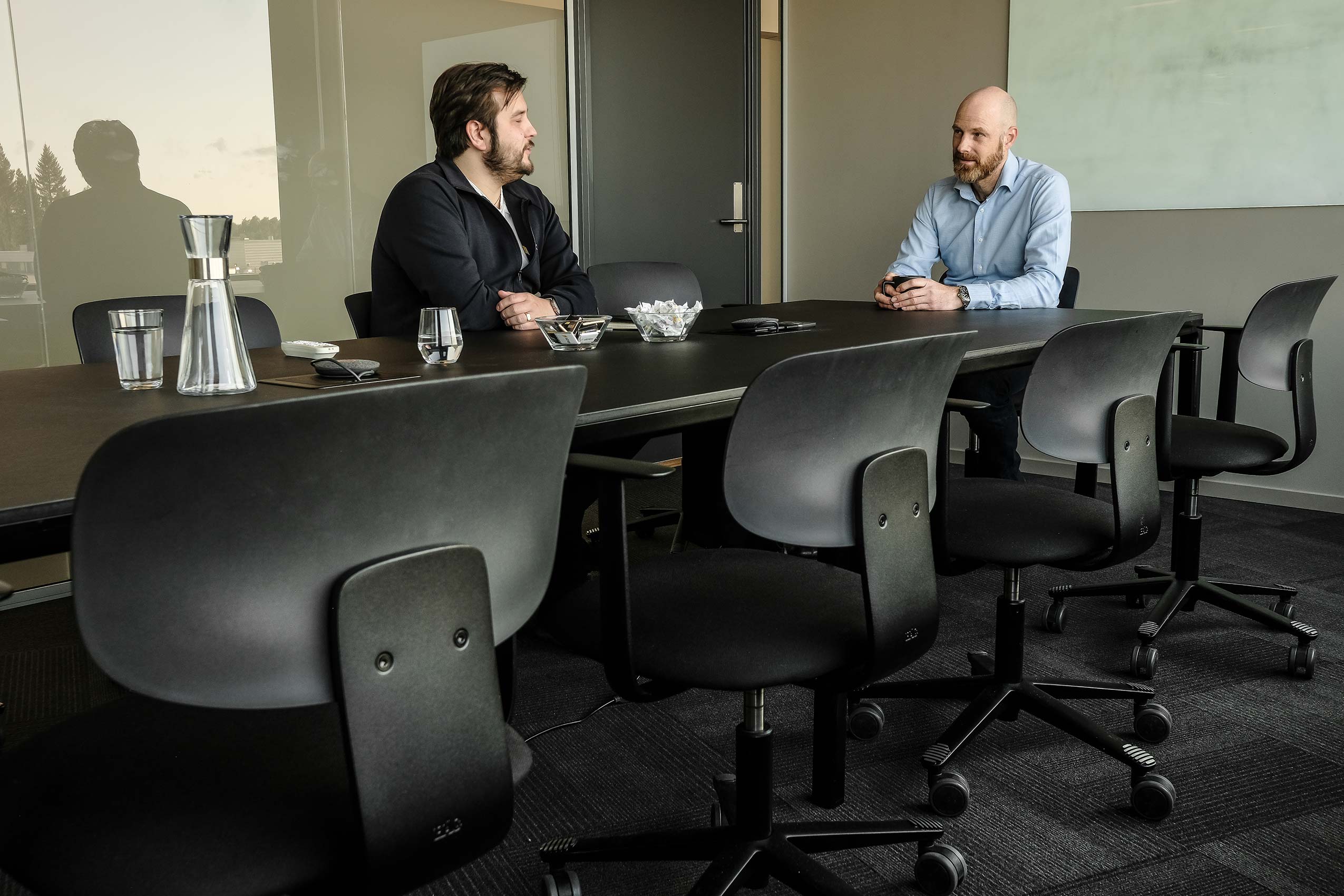 Two people sat in black HÅG Tion chairs around a meeting table at Strex's new office