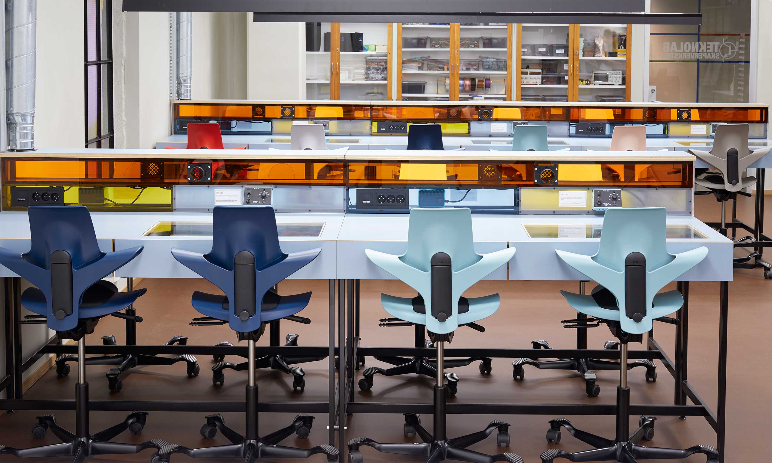 another angle of colourful HÅG Capisco Puls chairs at workstatins with electric sockets at Teknolab, Oslo