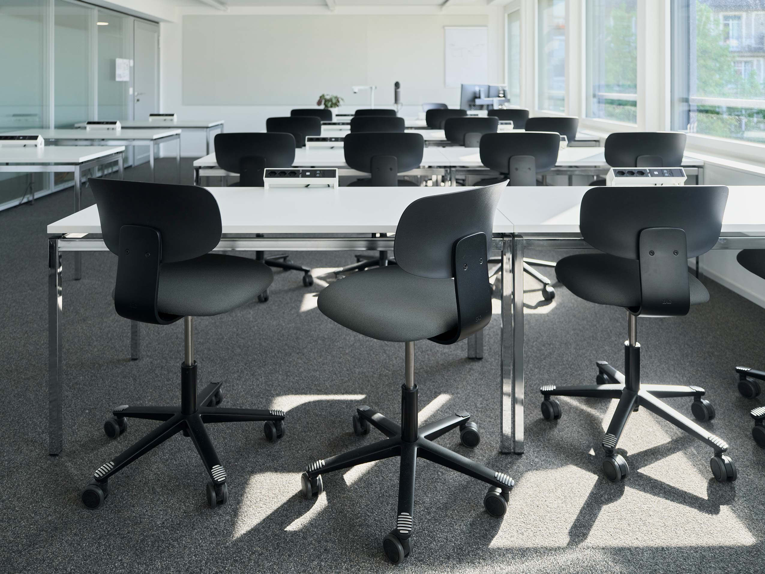 a classroom with HÅG Tion chairs at several rows of white desks
