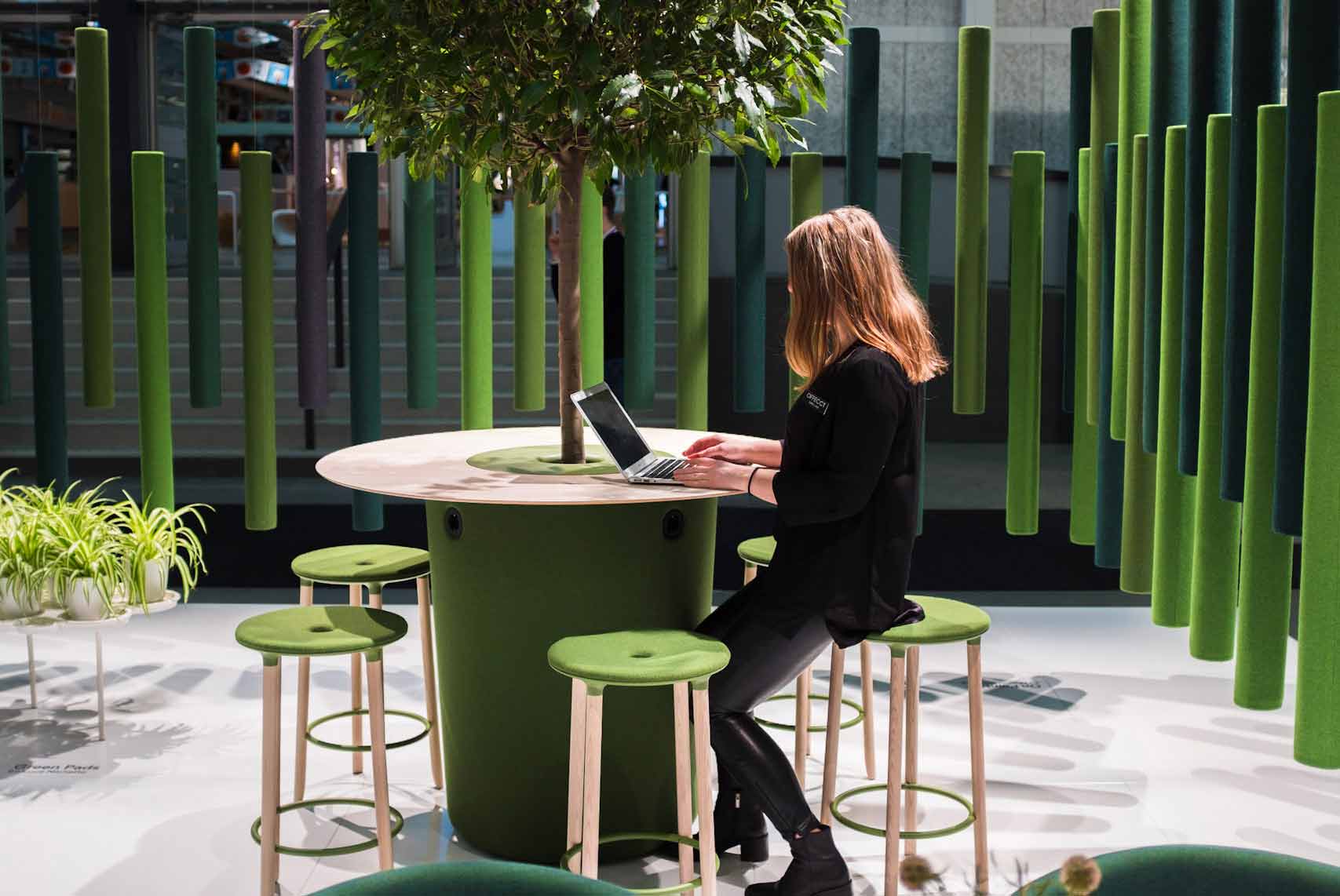 lady sitting at Offecct on point table with green offecct sound sticks in the background