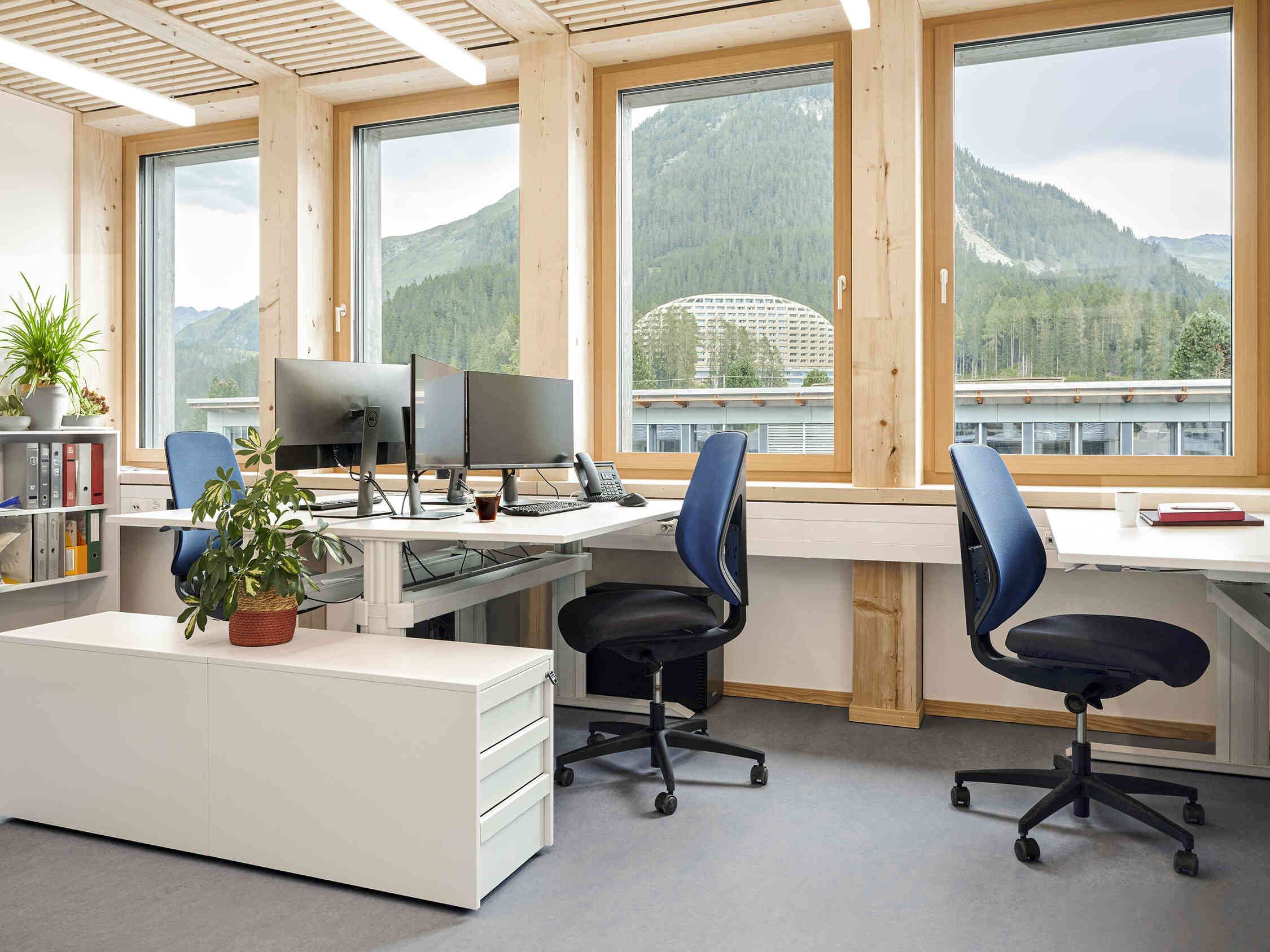 interior of office with mountain view through the windows, and 3 Giroflex chairs around workstations