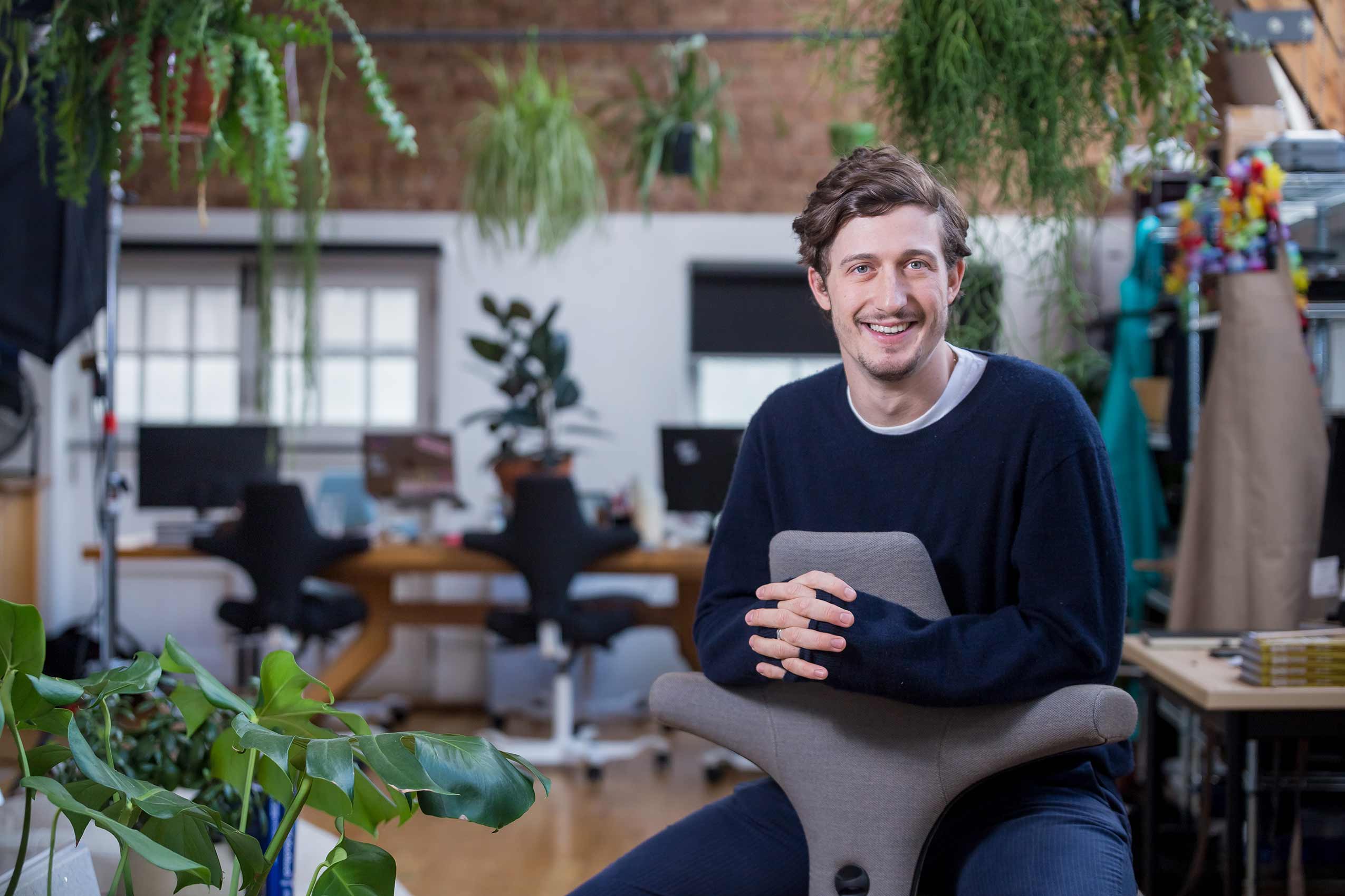 Ben Lebus founder of mob kitchen sitting on a hag capisco chair in kitchen studio