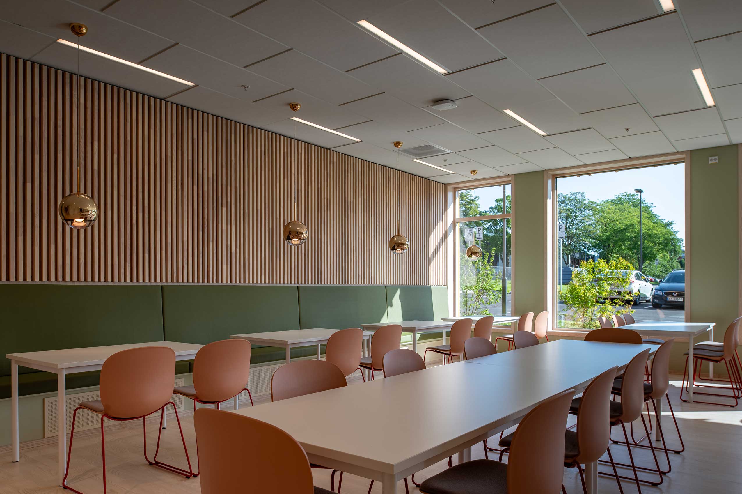 bright room with Profim Noor chairs arranged around tables in a dining room layout, with wooden walls and greenery visible in the window outside
